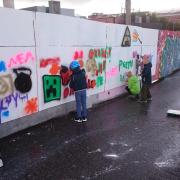 Lapsia maalaamassa Suvilahden luvallisella graffitiseinällä vuonna 2019.