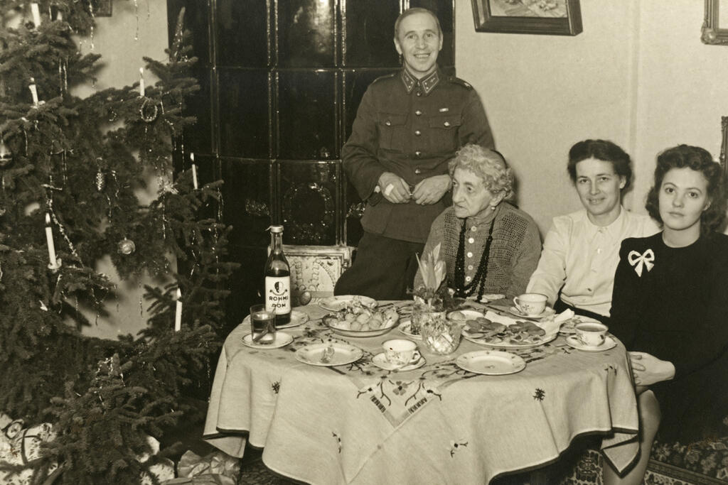 Fotograf Constantin Grünberg firar jul i vapendräkt år 1942 på Vespervägen 2. Vid bordet sitter hans mor Eugenie, hans fru Renate och en okänd kvinna. Foto: Helsingfors stadsmuseum / Inez Grünberg