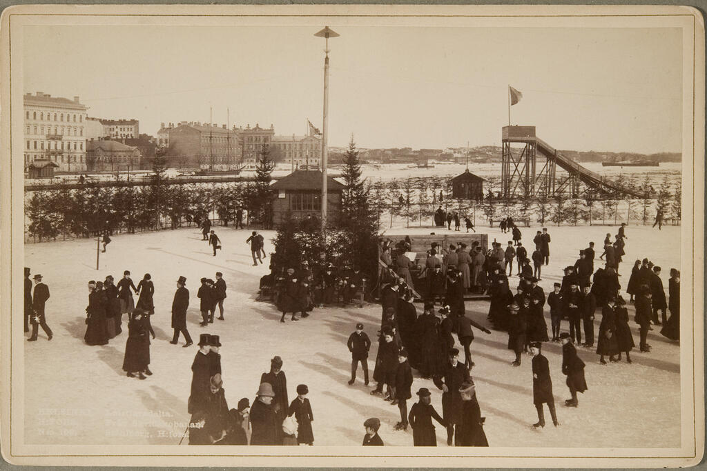 1870-luvulla perustettu Helsingfors Skridskoklubb teki Pohjoisrantaan talvisin jäälle muodikkaan luistinradan, joka oli tärkeä kohtaamis- ja näyttäytymispaikka. Sähköä saatiin viereiseltä Borgströmin tupakkatehtaalta. Kuvaaja: Museovirasto / K. E. Ståhlberg