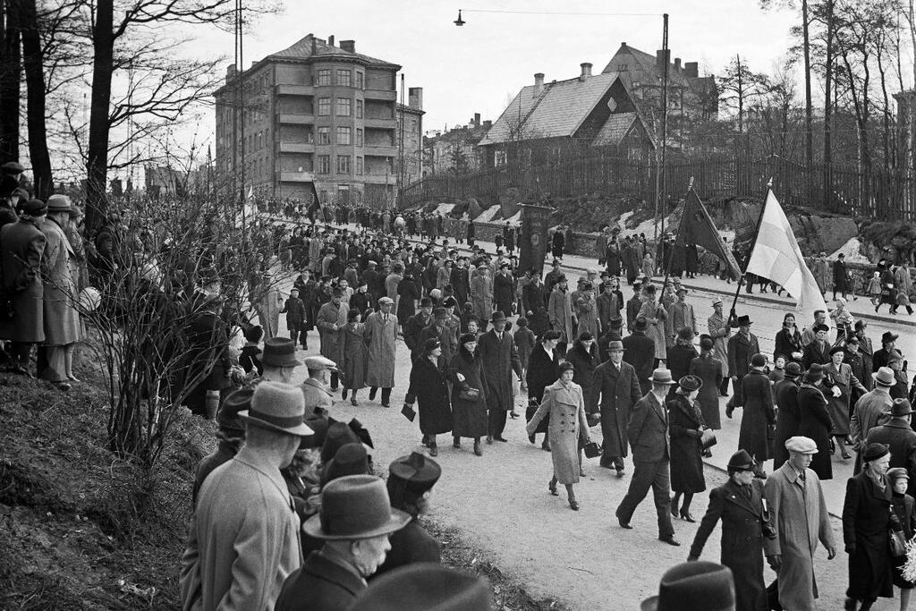 Arbetare marscherar längs Helsingegatan mot Tallbacken den första maj 1941. I bakgrunden syns Diakonissanstaltens byggnader, av vilka de mellersta senare har rivits och ersatts med nya. Foto: Museiverket / Hugo Sundström