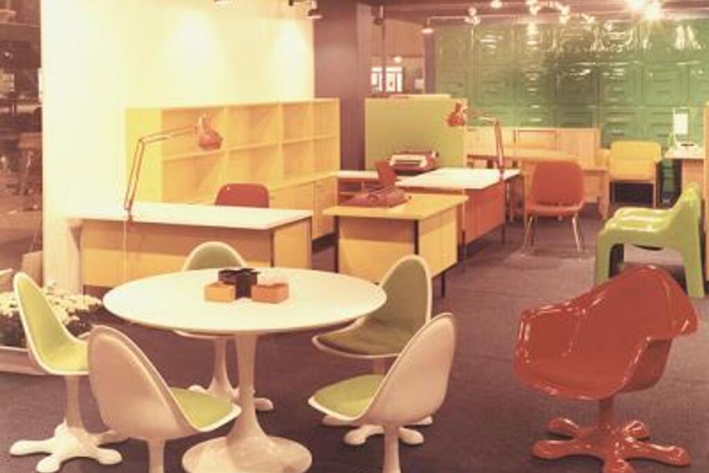 Askon julkisen tilan huonekaluja messuhallin näyttelyssä vuonna 1970. Kuvassa edessä vasemmalla on Eero Aarnion suunnittelemat valkorunkoiset ja punarunkoinen Orion-tuoli. Taustalla näkyy Ahti Kotikosken suunnittelema vihreä Anatomia-tuoli. Askon messuosaston suunnitteli Ilse Töyrylä. Muovi oli 1960- ja 1970-luvulla äärimmäisen muodikas materiaali. Kuvaaja: Lahden museot