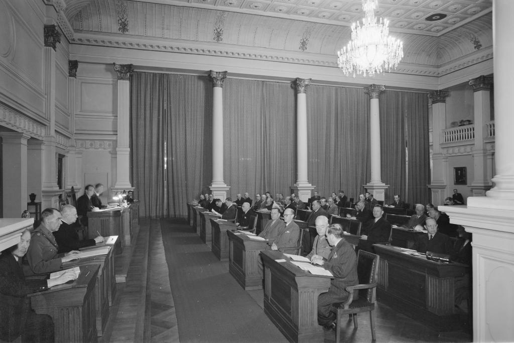 Helsingin kaupunginvaltuuston kokous 1940-luvun jälkipuoliskolla. Vuoden 1945 kunnallisvaalit olivat ensimmäiset yhdeksään vuoteen. Vasemmiston nousu sähköisti asetelmia ja SKDL:stä tuli valtuuston suurin ryhmä. Porvarilliset puolueet säilyttivät kuitenkin enemmistönsä. Helsinkiläinen kunnallispolitiikka heijasti vuonna 1945 ajan yleisiä aatteellisia ja poliittisia painotuksia. Politiikan painopiste oli sodan jälkeisten kriisien ehkäisyssä, johon pyrittiin vahvistamalla yhteisöllisyyttä ja parantamalla kaupunkilaisten elinehtoja. Kuvaaja: Museovirasto / Pietinen 