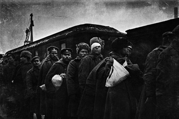 En grupp sårade ryska soldater står framför en tågvagn. En soldats ansikte är täckt av bandage.