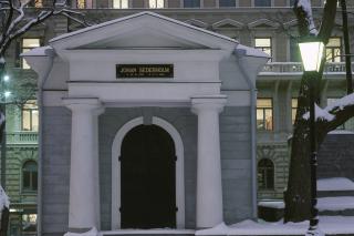 Foto av en liten stenbyggnad, dekorerad i nyklassisk stil. Ovanför dörren står det Johan Sederholm.