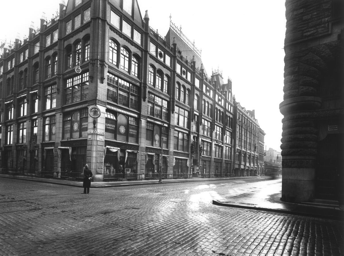 Aleksanterinkatu 13 kuvattuna noin vuonna 1910 kulmasta risteyksen toiselta puolen. Talon kulmalla seisoo mies, muuten kadut ovat tyhjät.