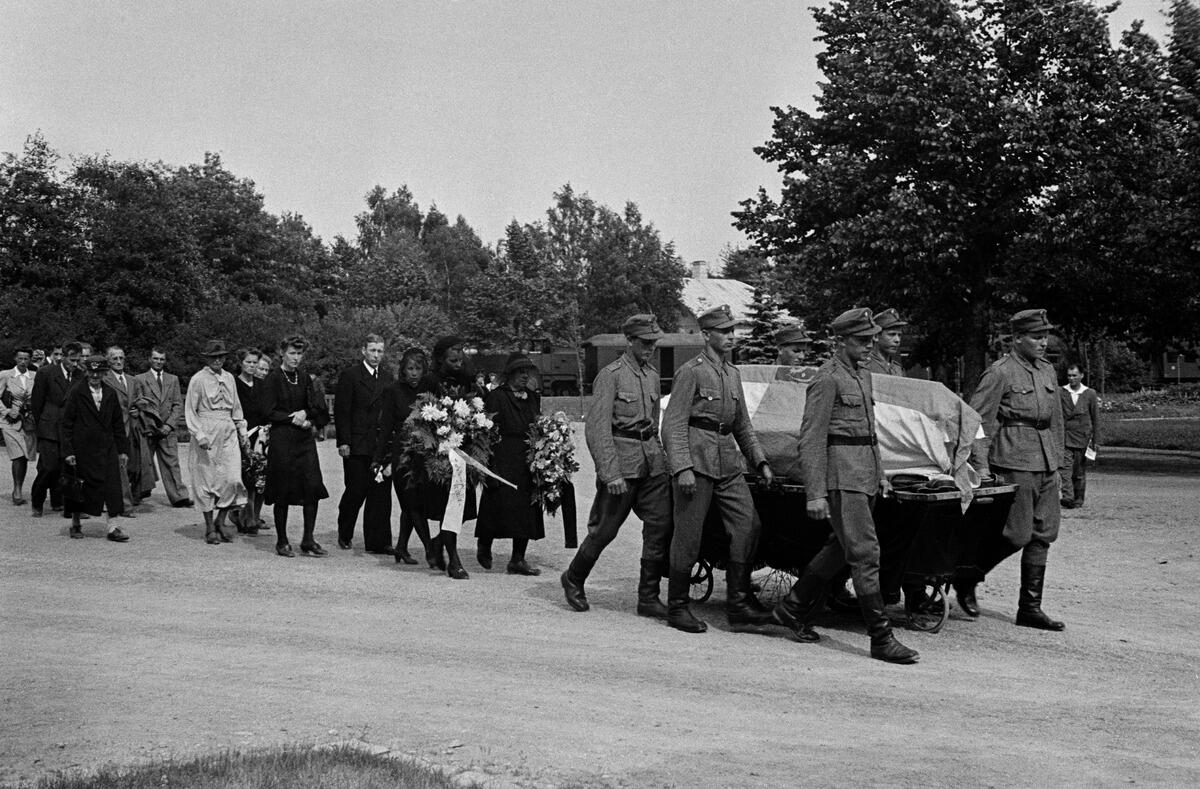 Pohjoinen hautausmaa (= Malmin hautausmaa). Hautasaatto, sotilaat kuljettavat lipulla peitettyä sotamies Jalo Laiton arkkua. Taustalla näkyy saattoväkeä kuljettanut hautausjuna hautausmaaradalla.