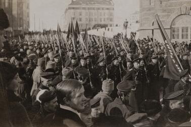 Rysska soldater firar i procession marsrevolutionen år 1917. Processionen består av uniformklädda män som bär flaggor.