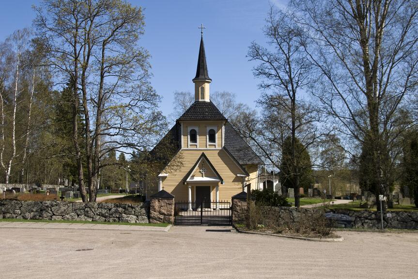 Kyrkobyggnad som omges av kyrkgård och en stenmur