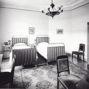 Hotelli Kämpin hotellihuone. Makuuhuone, jossa kaksi vuodetta, vaatekaappi, kirjoituspöytä ja tuoleja. 