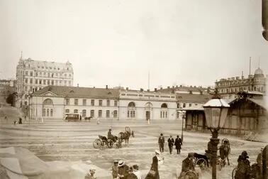 Hyrvagnar med sina hästar och herrskap vid Södra hamnen på Packhustorget. I bakgrunden det tidigare arméförrådet, från 1888 packhuset, Västra Hamngatan 10 (nuvarande Södra kajen 10). På gatan en hästdragen spårvagn. Bakom förrådet syns ett femvåningshus från 1960-talet vid hörnet av Unionsgatan 14 – Södra Magasinsgatan 3.