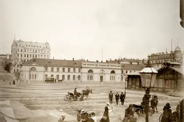 Hyrvagnar med sina hästar och herrskap vid Södra hamnen på Packhustorget. I bakgrunden det tidigare arméförrådet, från 1888 packhuset, Västra Hamngatan 10 (nuvarande Södra kajen 10). På gatan en hästdragen spårvagn. Bakom förrådet syns ett femvåningshus från 1960-talet vid hörnet av Unionsgatan 14 – Södra Magasinsgatan 3.