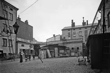 Aleksanterinkatu 52, sisäpiha. Sivuttain katsojaan seisoo nainen, jolla on lapsi sylissä. Kolme isompaa lasta seisoo rivissä keskellä pihaa. 