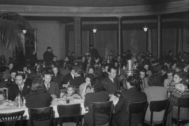 Lots of families gathered at long tables in a round restaurant hall.