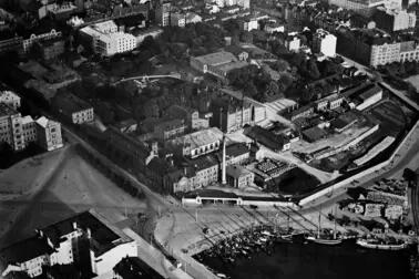 Flygbilden illustrerar Rödbergens och Sandvikens industriella historia. På bilden syns Sinebrychoffs fabriksområde med park, Bulevarden 40–42, Sandvikskajen 7, Maltgatan 1, Sandvikens bassäng och Sandvikens torg.