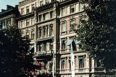 Hotell Kämps fasad fotograferad på sommaren. På Esplanaden syns en vit bil, i förgrunden står fyra kvinnor.