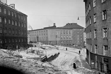 Flervåningshus och människor som går på en snöig gata.