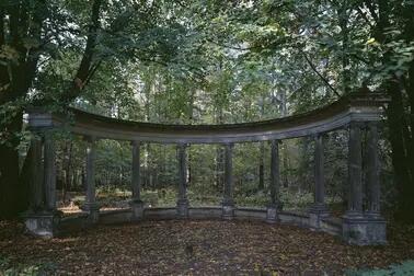 Harmaa pylväskaari metsän keskellä.