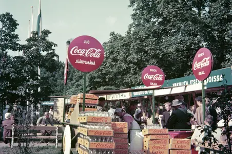Coca-Colan myyntipiste Hesperian puistossa. Pullokorit täyttävät myyntipisteen edustan, johon on kerääntynyt jonoa.