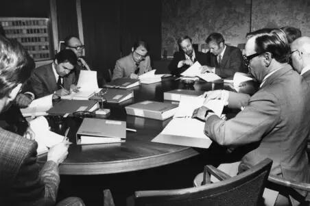 Metrokommittén sammanträder i Ämbetshuset i Berghäll på 1970-talet. Nio män sitter runt bordet som är full av tjocka pärmar..