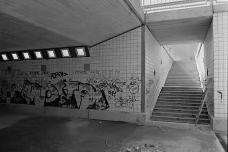 Graffiteja Porkkalankadun alikulkutunnelissa. Mustavalkoisessa kuvassa tunnelin seinään on kirjattu suuri määrä pieniä tageja ja yksi suurempi graffitimaalaus.