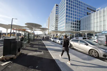 Vy mot Böle stationsplats. I förgrunden en busshållplats för en stomlinje, i bakgrunden höjer sig köpcentret Triplas höga byggnader.