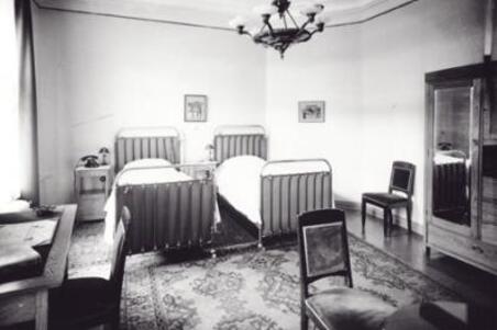 Hotelli Kämpin hotellihuone. Makuuhuone, jossa kaksi vuodetta, vaatekaappi, kirjoituspöytä ja tuoleja. 