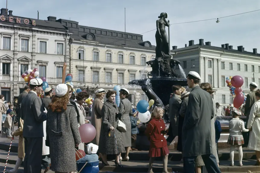 Aikuisia ja lapsia kokoontuneena Havis Amandan ympärille. Joillakin on ylioppilaslakki, joillakin kädessään ilmapallo.
