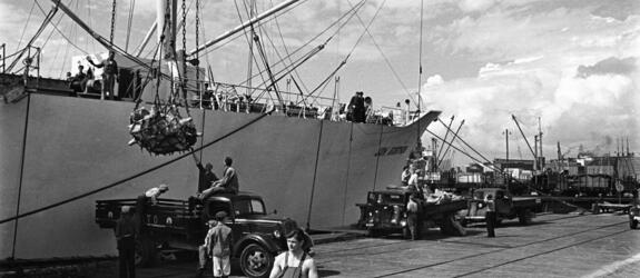 Lasten av ett handelsfartyg håller på att lossas med vinscher till lastbilsflak i Sörnäs hamn.
