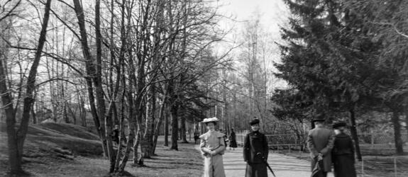 Two elegantly dressed older women are walking towards the camera on an avenue in Kaivopuisto.