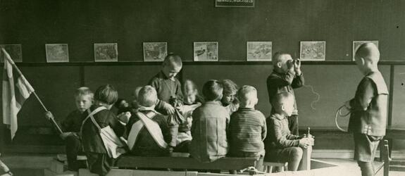 Ryhmä lapsia on rakentanut isoista palikoista "laivan" huoneen lattialle. Kymmenkunta lasta istuu "laivan" kyydissä. 