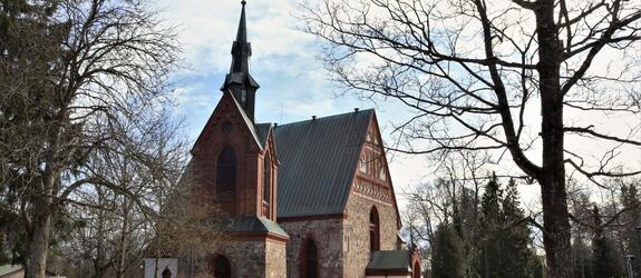 Fotografi av medeltida stenkyrka omgiven av smältande snö