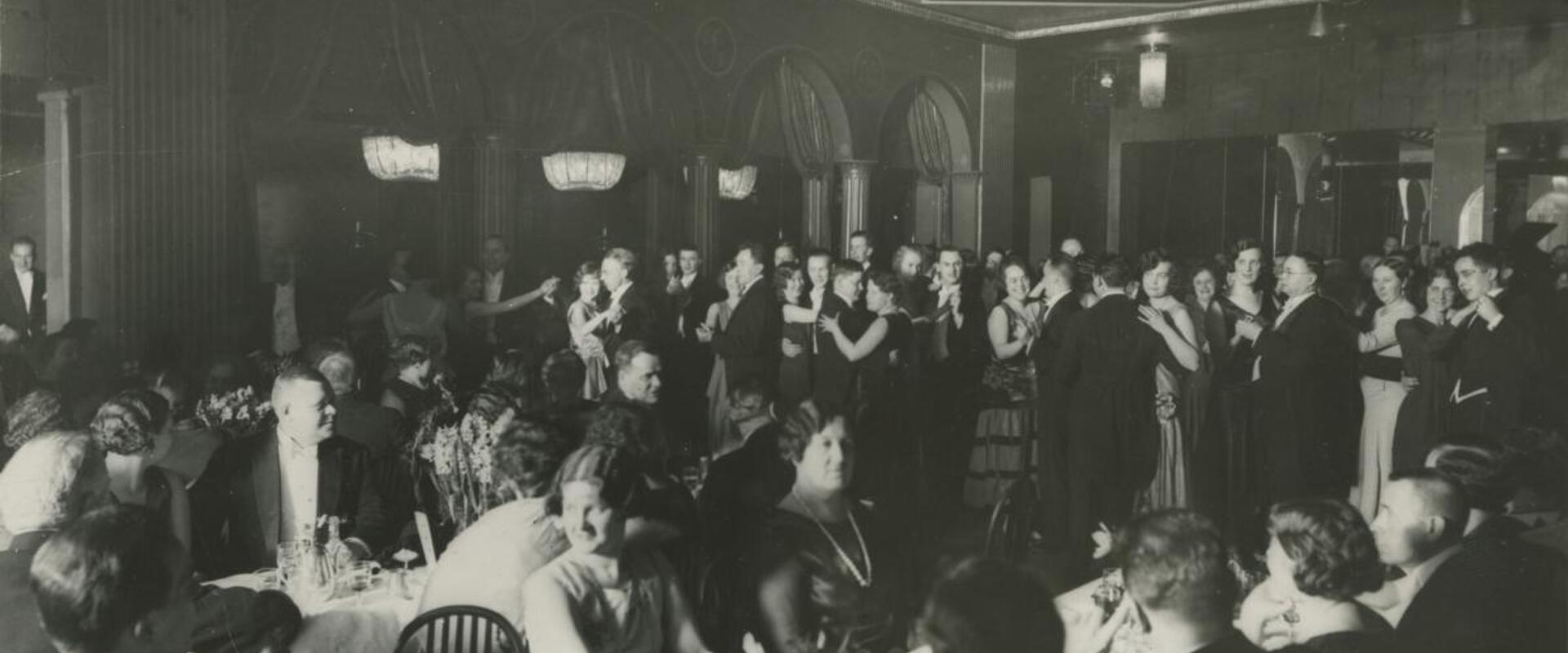 Kansallis-Osake-Pankin 40-vuotisjuhlat. Asiakkaita aterioimassa, taustalla ihmisiä tanssimassa.