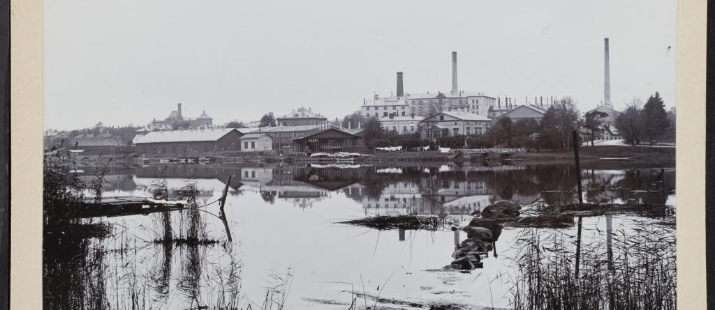 Töölön sokeritehdas Töölönlahden yli kuvattuna. Kuvassa Töölönlahden ranta on huomattavasti nykyistä tiiviimmin rakennettua.