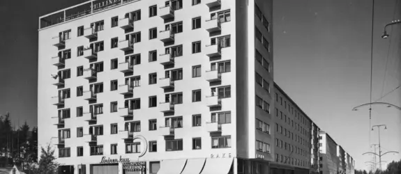 Åbovägen 90 (= Mannerheimvägen 118). Tullbommens byggnad. Arkitekt Olli Pöyry, färdig 1940. En ljus åtta våningars byggnad vars övre del bär neonbokstäverna Tullinpuomi Tullbommen och högra kanten KINO.