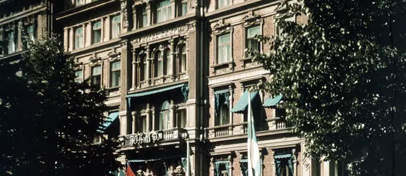 Hotell Kämps fasad fotograferad på sommaren. På Esplanaden syns en vit bil, i förgrunden står fyra kvinnor.