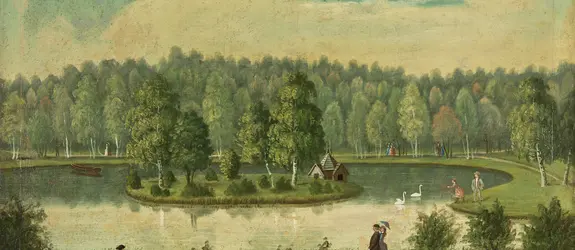 Svandammen i Kajsaniemi med ön i mitten. På ön syns svanarnas husliknande bo. Människor promenerar på den väg som går runt dammen.