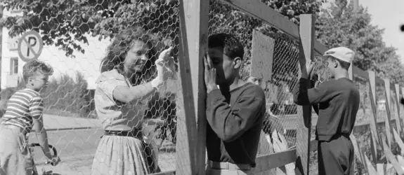 Helsingin olympialaiset 1952. Urheilijat jakavat nimikirjoituksia verkkoaidan takaa Käpylän Kisakylässä.