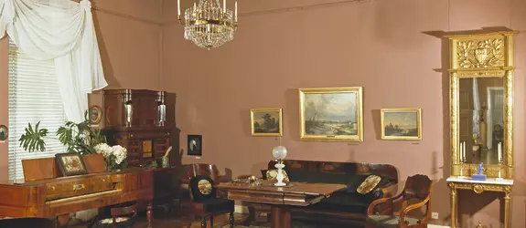 Rummet är inrett med orientaliska mattor, möbler i ädelträ, en stor väggspegel med förgylld ram samt en kristallkrona.