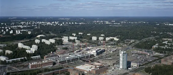 Flygbild över stadsdelen Östra centrum från söder mot norr. I förgrunden Österleden och nya byggnader, i bakgrunden skog och äldre höghus.