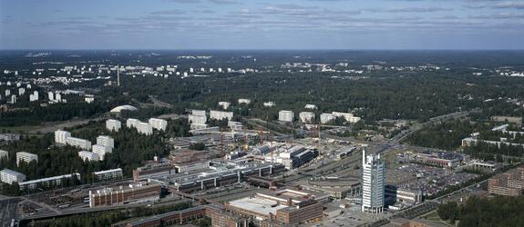 Flygbild över stadsdelen Östra centrum från söder mot norr. I förgrunden Österleden och nya byggnader, i bakgrunden skog och äldre höghus.