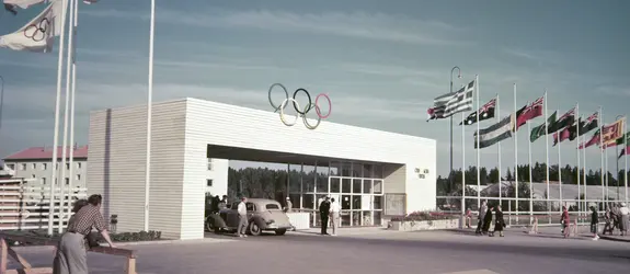 Käpylään rakennetun Olympialaisten kisakylän portti Koskelantiellä. Porttia ympäröivät osallistujamaiden liput.