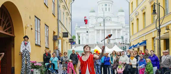 I förgrunden syns en jonglör som kastar käglor. Bakom honom står en folkhop och tittar på, och i bakgrunden syns Domkyrkan.