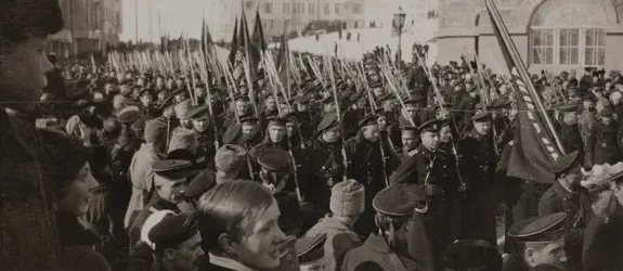 Venäläiset sotilaat juhlivat kulkueessa maaliskuun vallankumousta vuonna 1917. Kulkue on täynnä univormupukuisia miehiä, jotka kantavat lippuja.