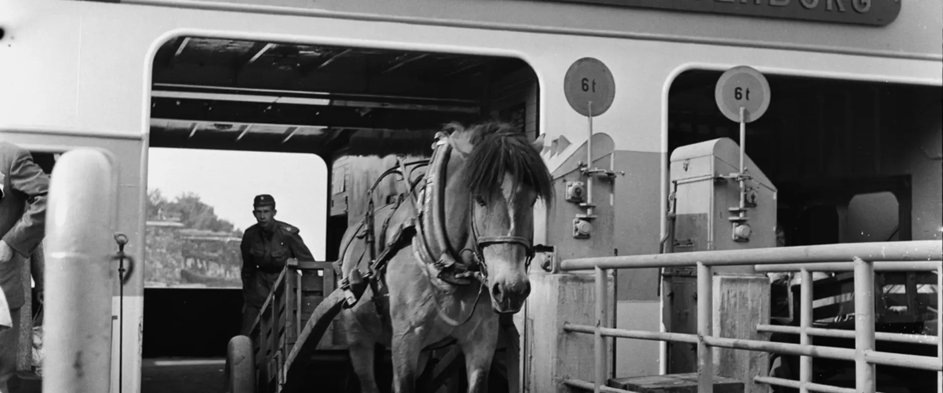 Färjan till Sveaborg har anlänt till bryggan på Stora Öster Svartö. Från fartyget kommer en hästkärra med en man sittande i vagnen.