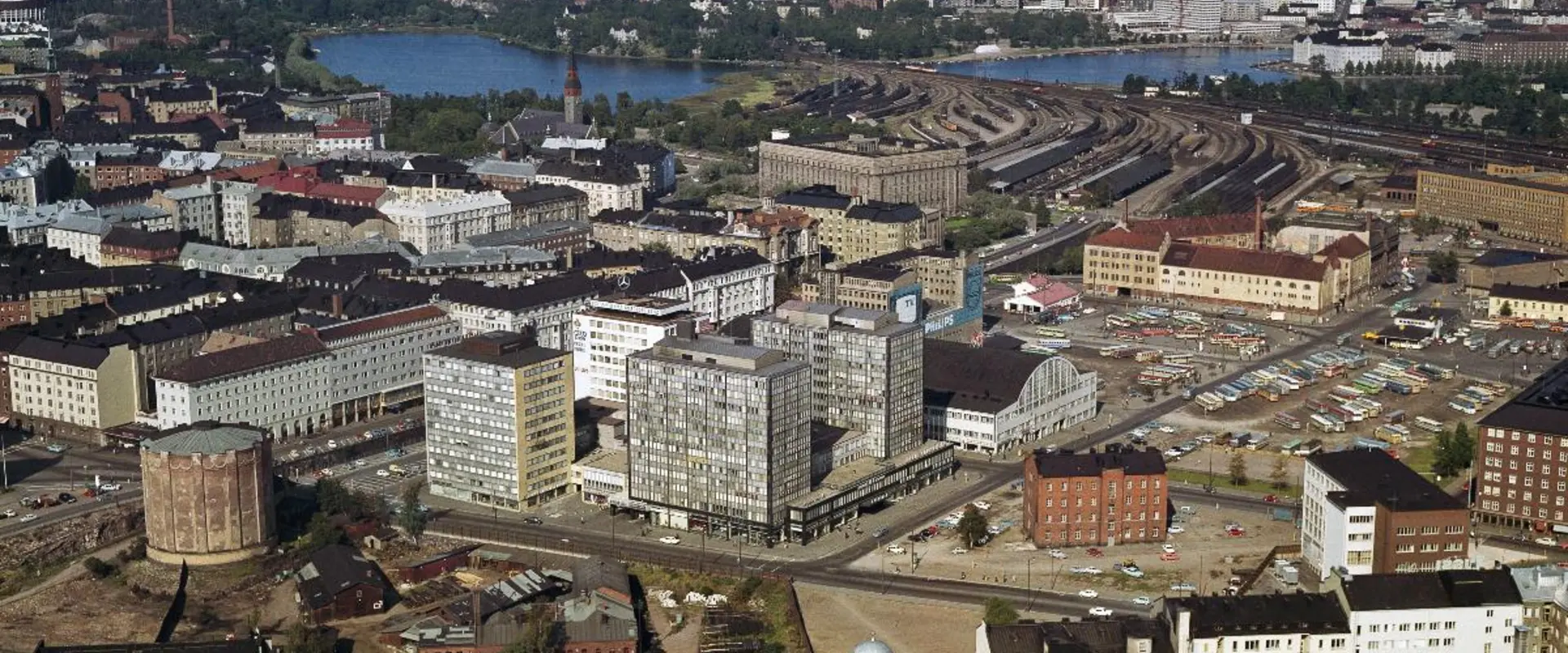 Kamppi, keskellä Autotalo ja Tennispalatsi. Vasemmalla vuonna 1907 rakennettu Kampin kaasukello, joka purettiin vuonna 1968. Autotalon edessä kasarmi, joka purettiin samoihin aikoihin. Bussien pysäköintikentän paikalla on nykyään Kampin keskus. Kentän takana on Maanviljelijäin Maitokeskuksen rakennus.