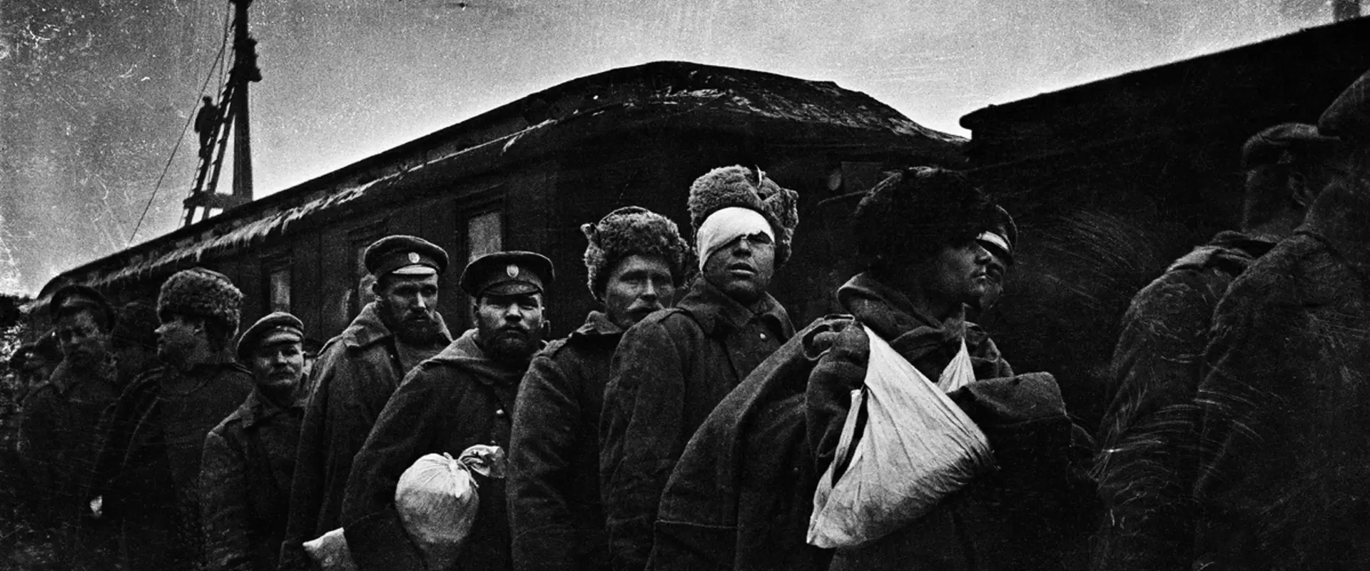 En grupp sårade ryska soldater står framför en tågvagn. En soldats ansikte är täckt av bandage.