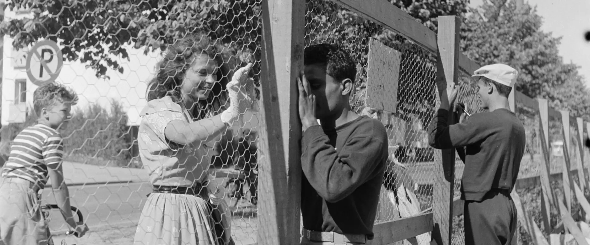 Helsingin olympialaiset 1952. Urheilijat jakavat nimikirjoituksia verkkoaidan takaa Käpylän Kisakylässä.