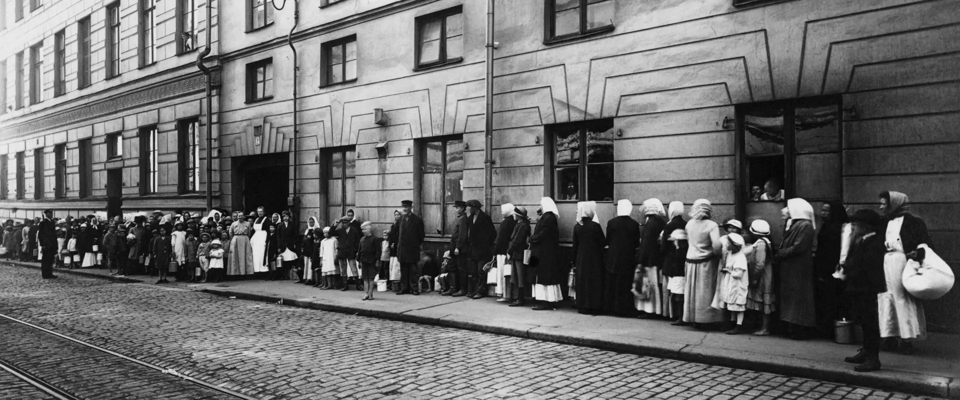 Kvinnor i en lång kö för livsmedelskort på Katarinagatan, utanför Helsingfors stads livsmedelsnämnds kortkansli vid stadshuset.