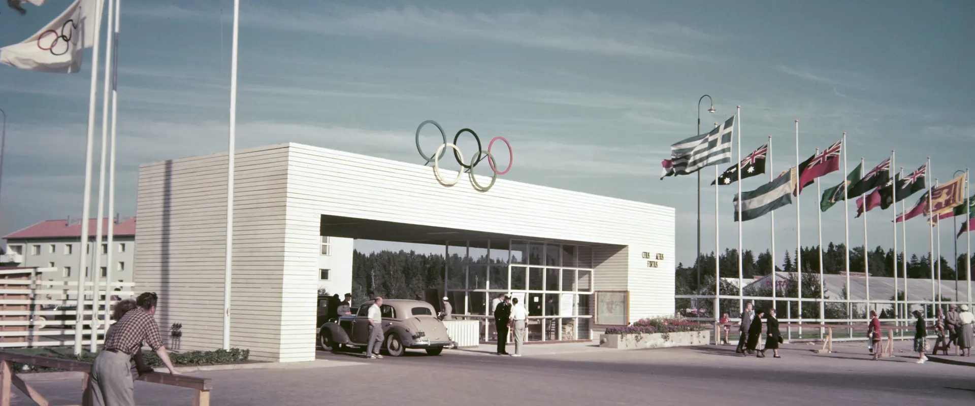 Käpylään rakennetun Olympialaisten kisakylän portti Koskelantiellä. Porttia ympäröivät osallistujamaiden liput.