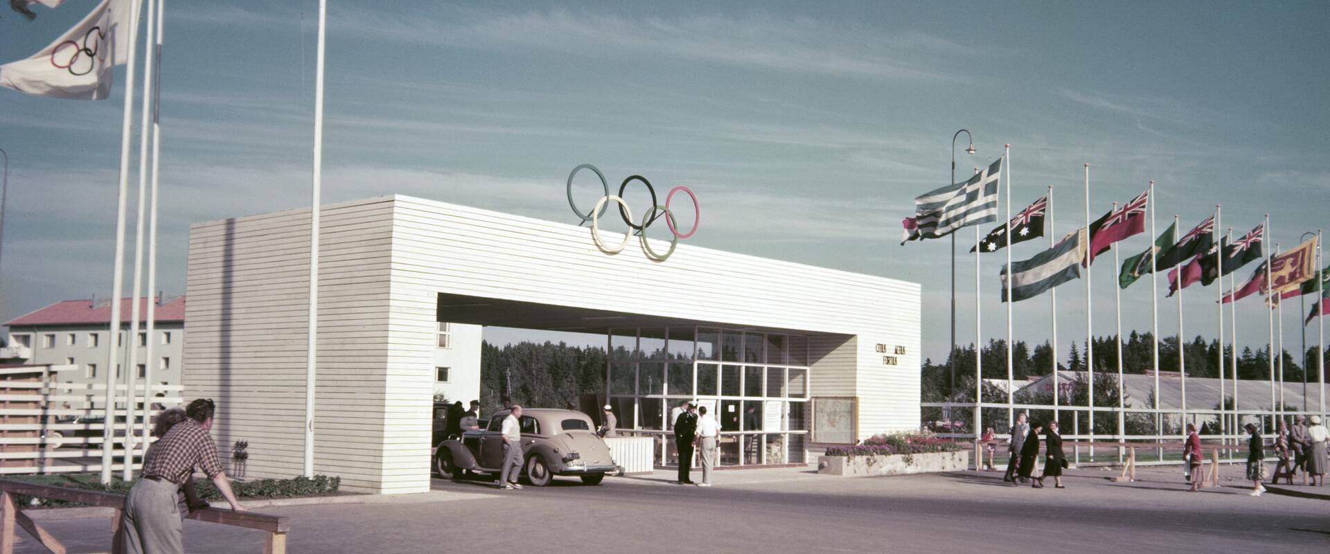 Käpylään rakennetun Olympialaisten kisakylän portti Koskelantiellä. Porttia ympäröivät osallistujamaiden liput.